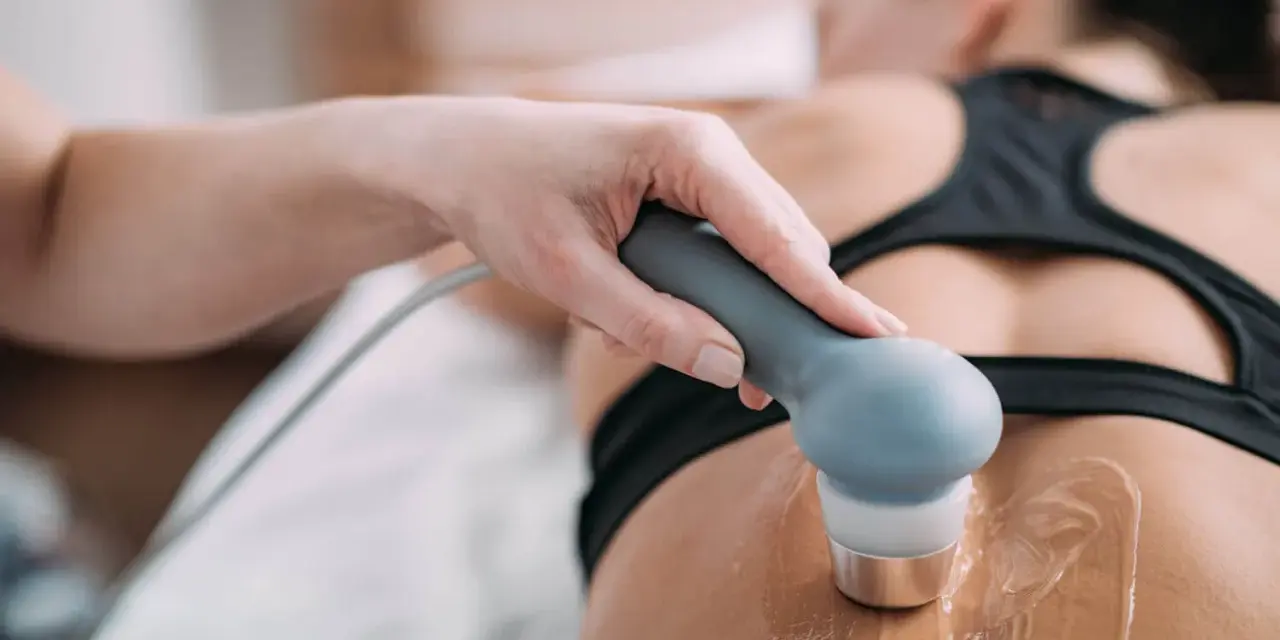 Therapeutin führt Ultraschall Physiotherapie am Rücken einer Patientin durch. Gel auf der Haut für die Behandlung.