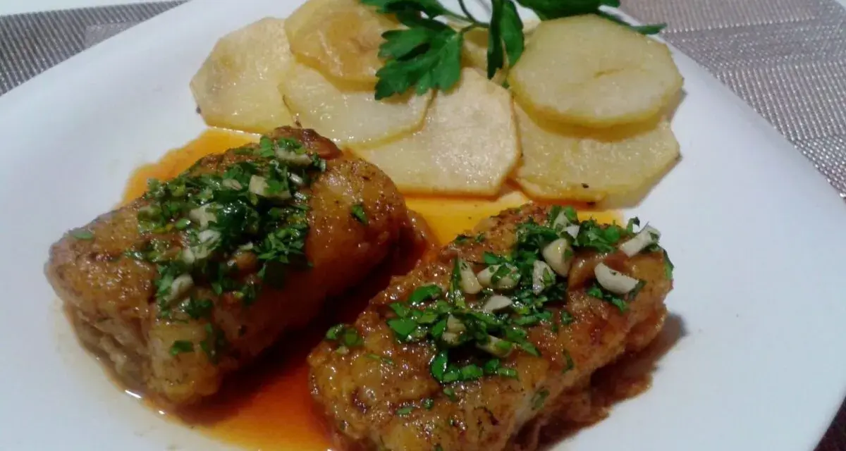 Dos trozos de bacalao a la llauna con patatas y perejil.