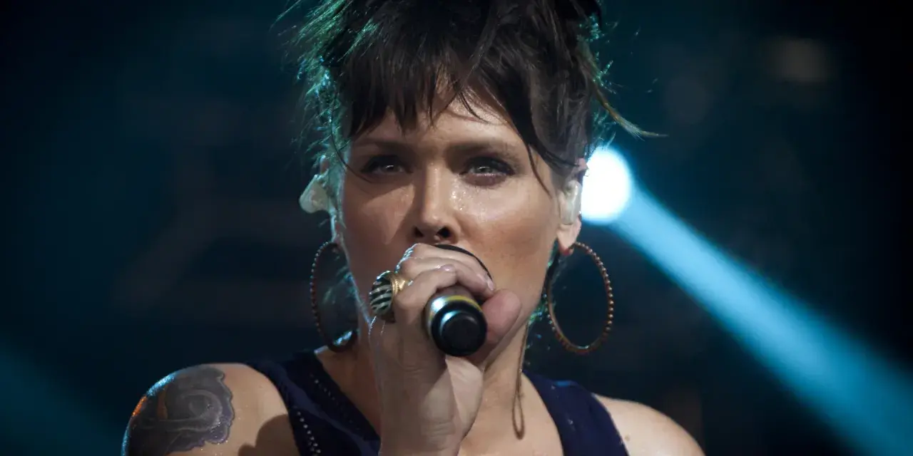 Beth Hart z tatuażem na ramieniu, w okrągłych kolczykach, śpiewa do mikrofonu. Choć nie widać jej dzieci, jej energia na scenie jest jak dla nich.