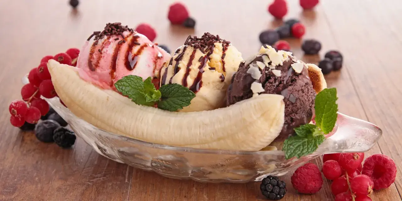 Ein klassisches Banana Split Eis mit drei Kugeln Eis, garniert mit Beeren und Schokostreuseln.