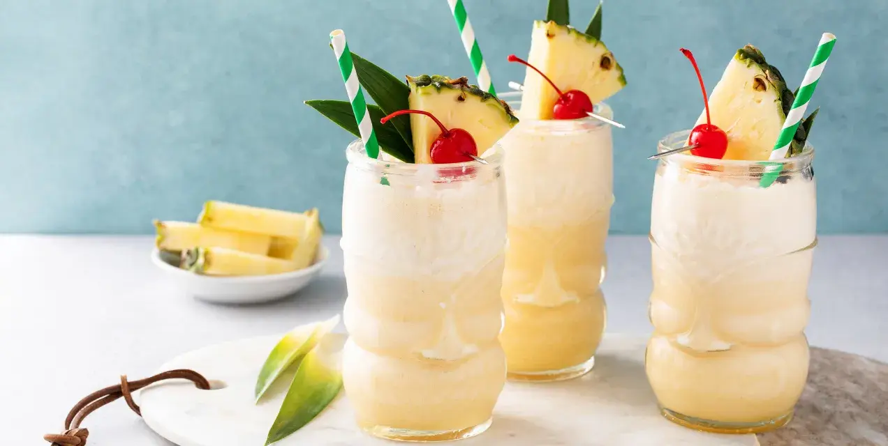Trzy orzeźwiające drinki bezalkoholowe Mocktail kontra klasyczny koktajl, udekorowane ananasem i wiśnią.