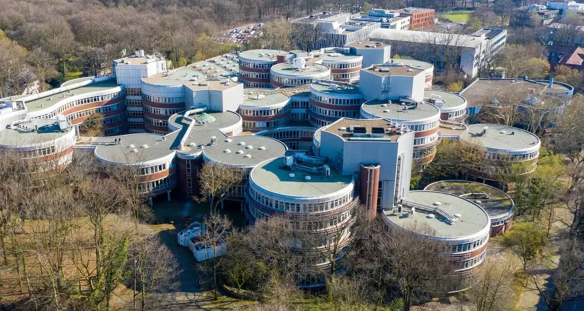 Einzigartige Architektur auf dem **Campus Duisburg**. Runde Gebäude mit vielen Fenstern gruppieren sich zu einem futuristischen Komplex inmitten von Bäumen.