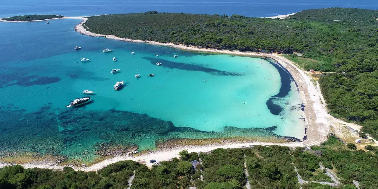 Turkusowa zatoka z łodziami, jedna z najpiękniejszych plaż w Chorwacji.