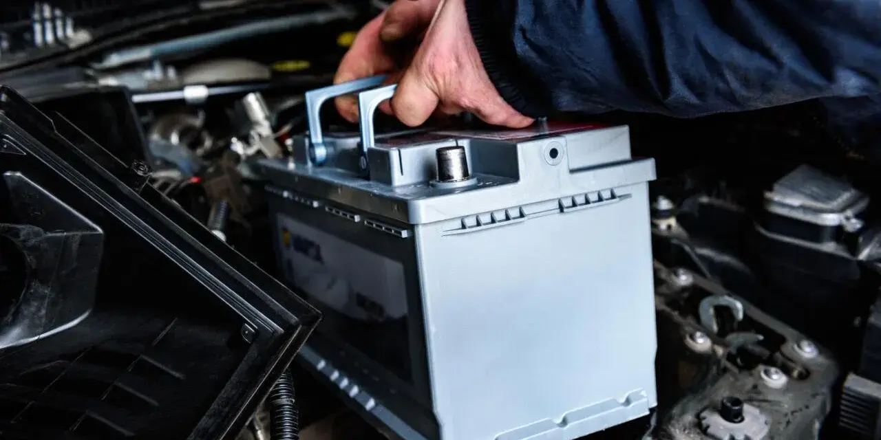 Mano che inserisce una nuova batteria. La batteria della macchina serve per avviare il motore e alimentare i sistemi elettrici.