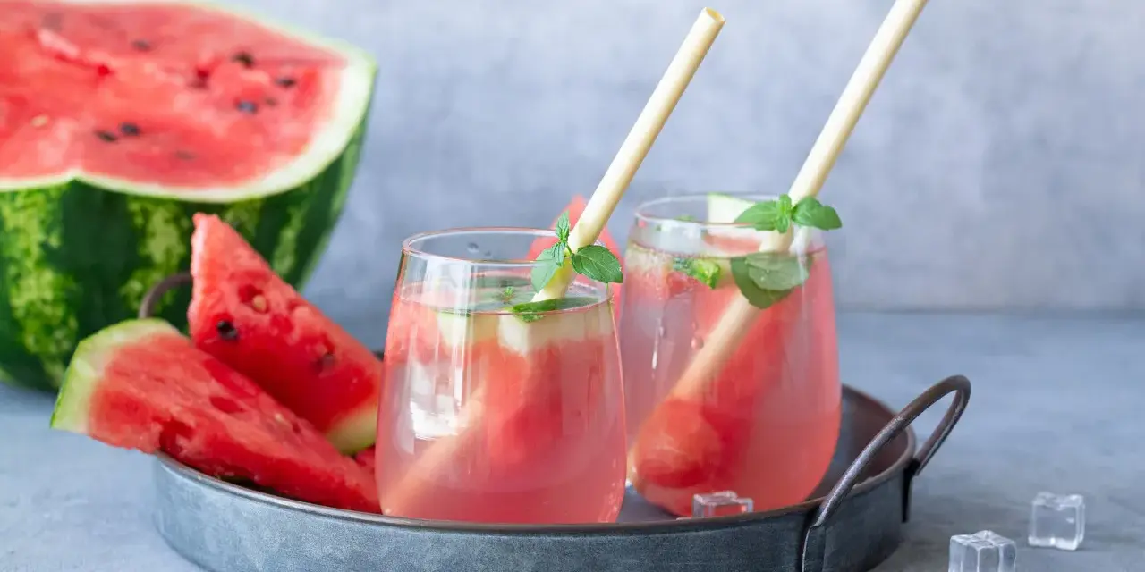 Orzeźwiający drink z arbuzem i miętą, podany na tacy z kawałkami arbuza i kostkami lodu. Idealny na upalne dni.
