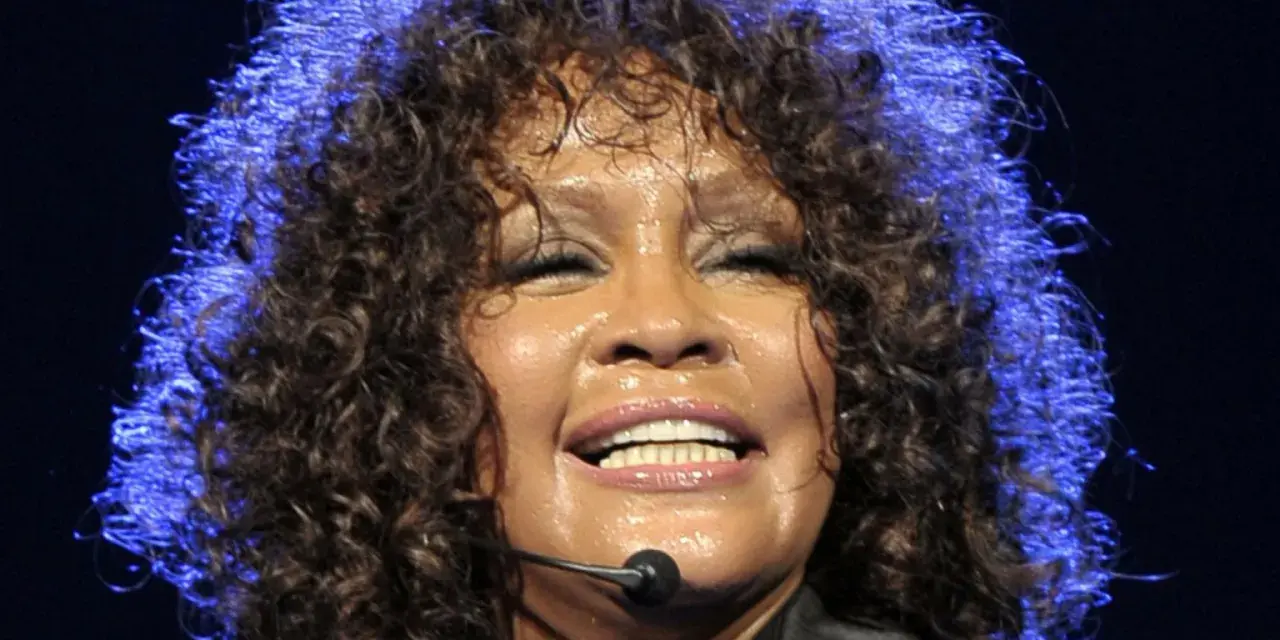 Whitney Houston z zamkniętymi oczami, w pełni emocji, pokazuje niesamowitą **skalę głosu**.