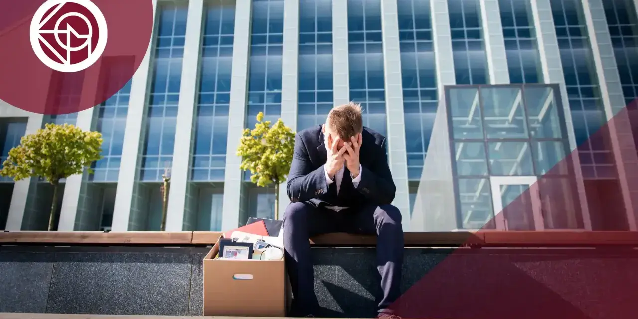 Hombre con caja de pertenencias, sentado frente a un edificio. ¿Me pueden despedir si estoy cubriendo una baja?