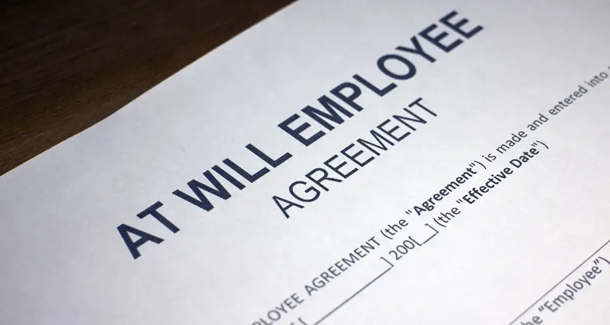 Close-up of an "At Will Employee Agreement" document, illustrating what does at-will employment mean: either party can terminate the relationship at any time.
