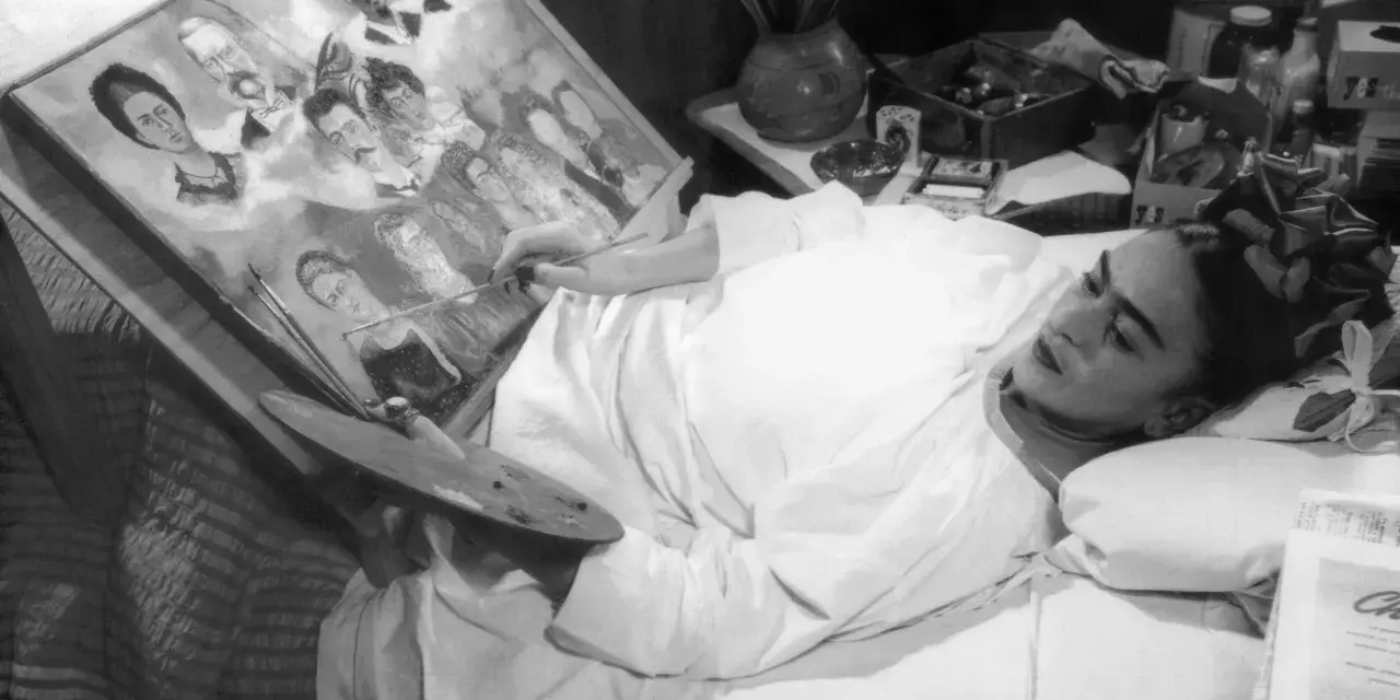 Frida Kahlo målar i sängen, omgiven av sina porträtt av familj och vänner, kanske sina syskon.