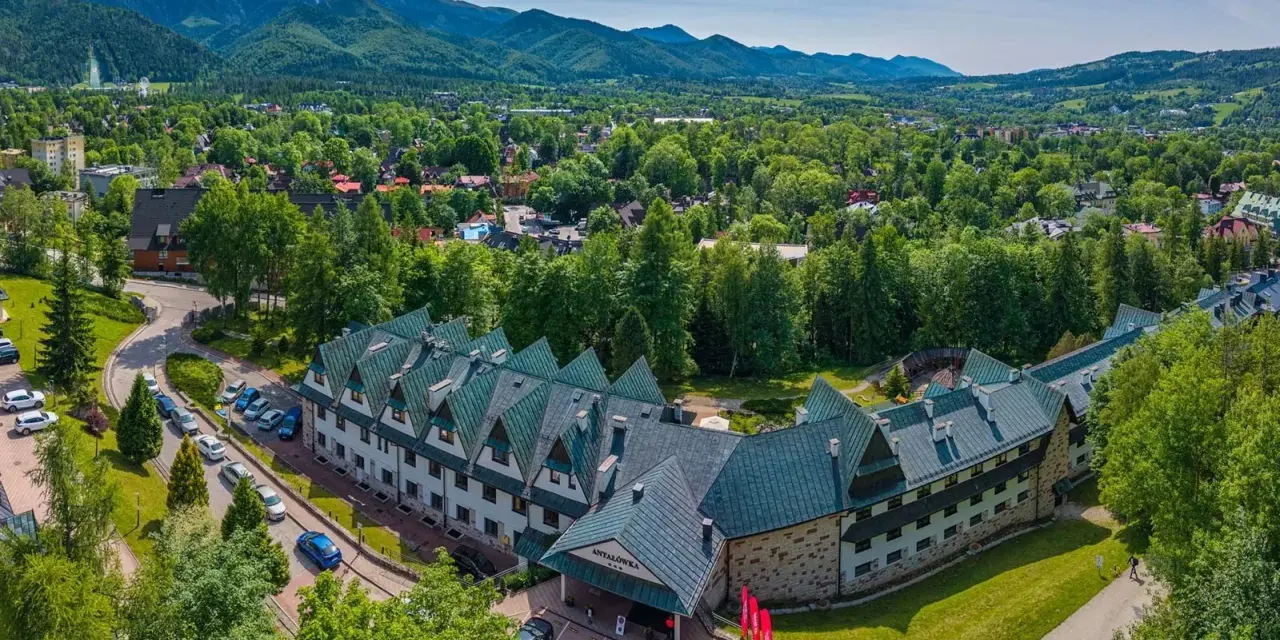 Widok z lotu ptaka na hotel Antałówka w Zakopanem, otoczony zielenią i górami w tle.