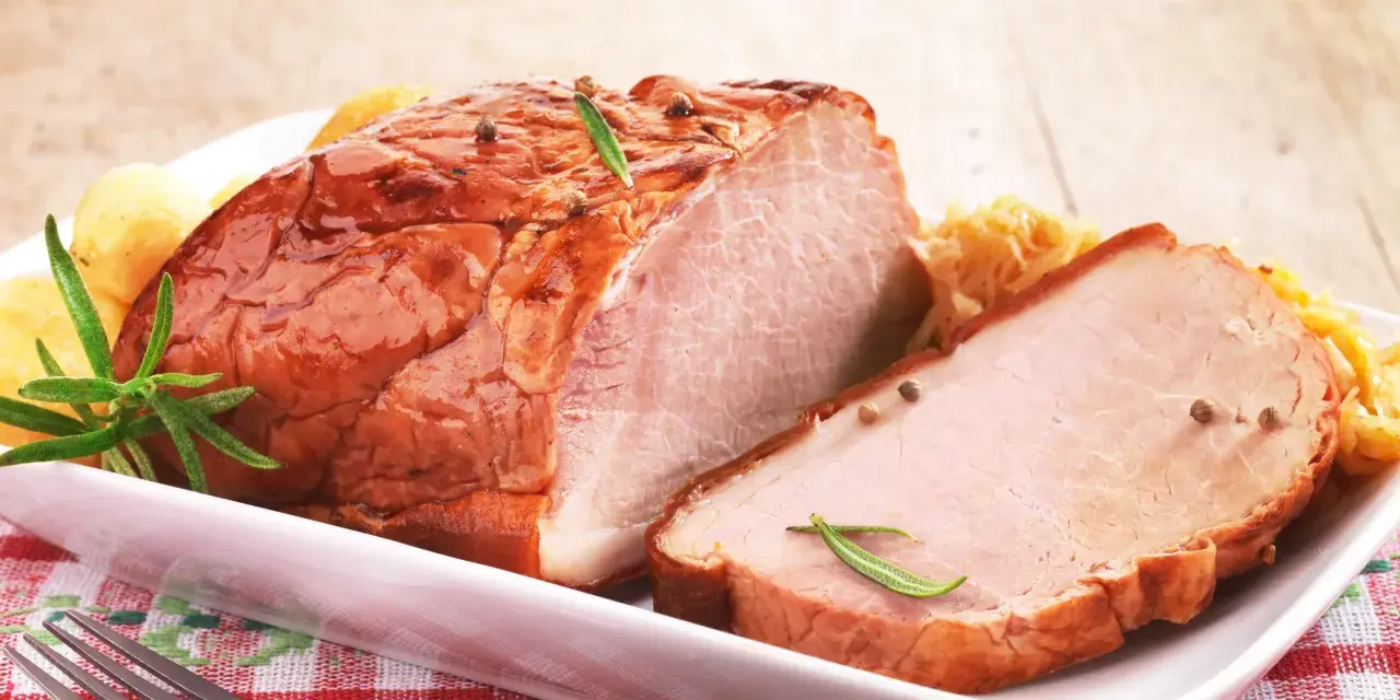Pyszny, pieczony schab na wielkanoc, udekorowany rozmarynem i ziarnami pieprzu, podany z ziemniaczkami i surówką.