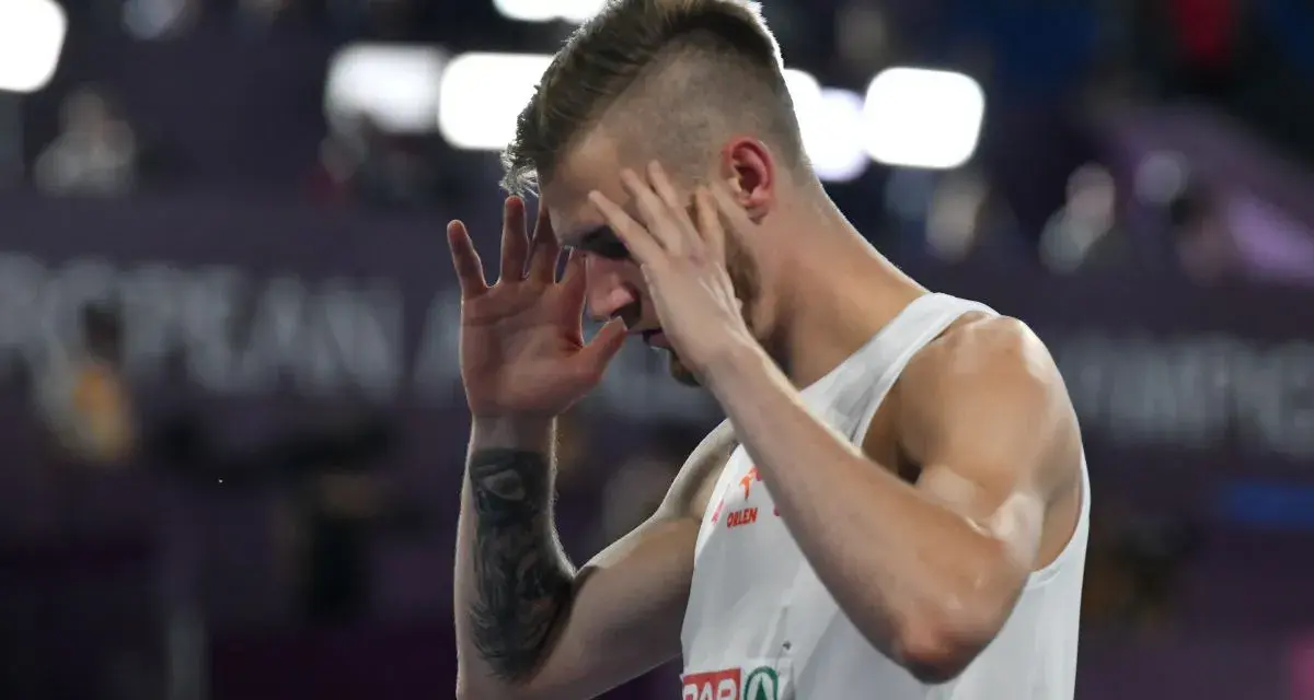 Norbert Kobielski, lekkoatleta, zamyka oczy, skupiając się przed ważnym startem.