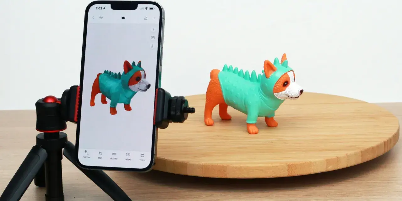 A phone on a tripod captures a toy dog, demonstrating 3D scanning for 3D printing.