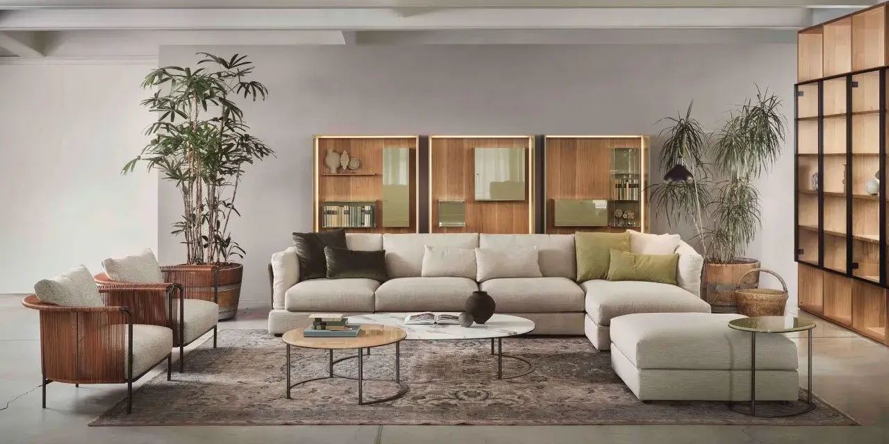 Un salotto moderno con divano componibile color tortora, poltrone in vimini e piante verdi.
