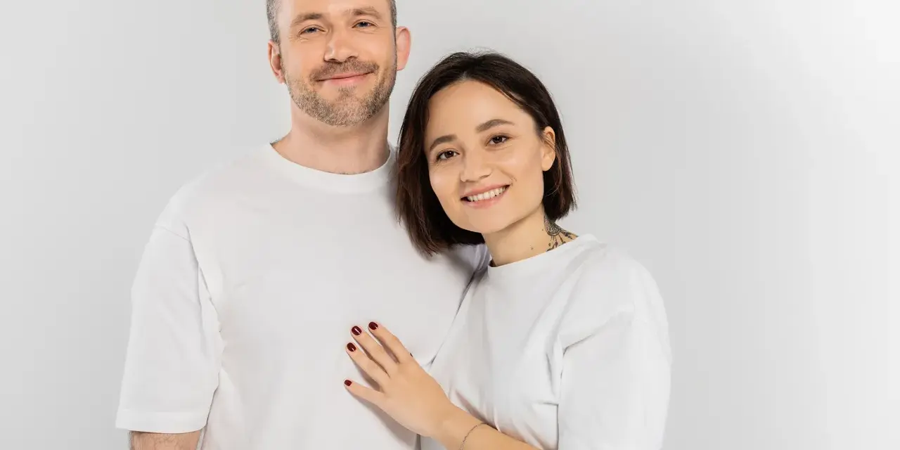 Uśmiechnięta para, on z zarostem, ona z tatuażem na szyi. Idealni do rozmowy o pytania na randkę.