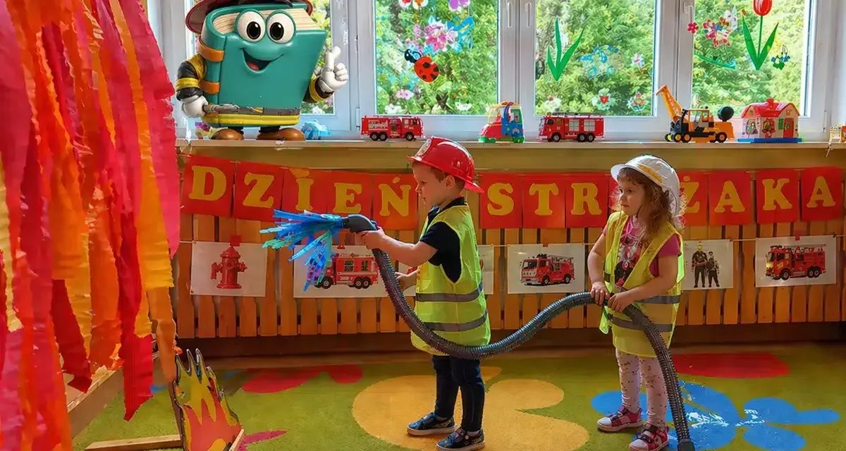 Dzieci gaszą pożar, świetne pomysły na dni otwarte w przedszkolu! Maskotka-książka w stroju strażaka zachęca do zabawy.