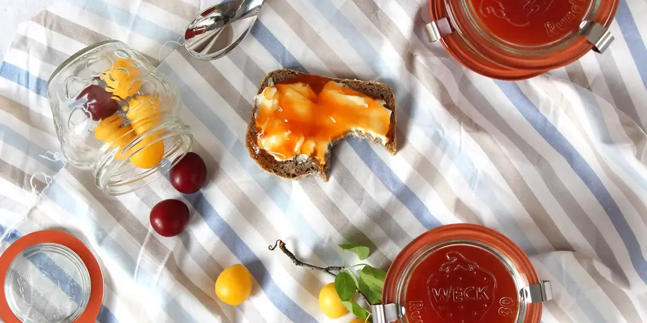 Kriecherl-Marmelade auf Brot, Gläser und frische Früchte. Perfekt für leckere Kriecherl Rezepte.