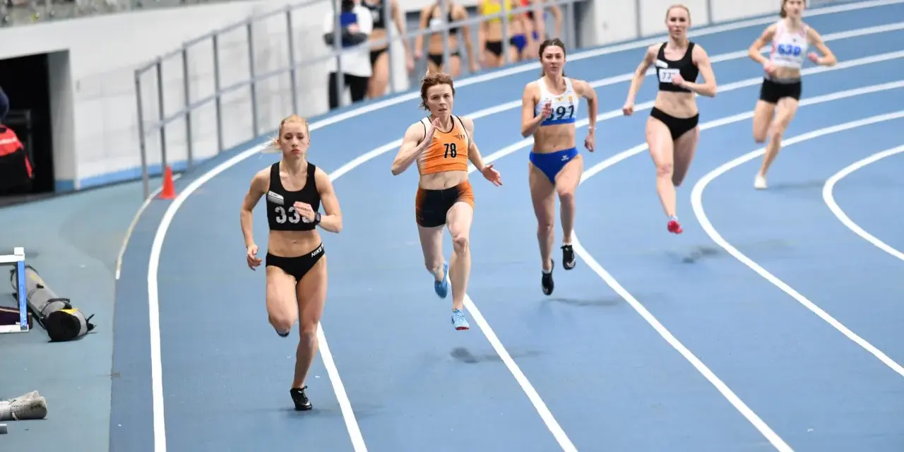Aneta Lemiesz biegnie w zawodach lekkoatletycznych, walcząc o zwycięstwo na bieżni.