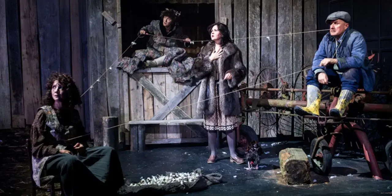 Scena z dramatu. Cztery postacie w wiejskiej scenerii, napięcie w powietrzu. Co to za dramat?