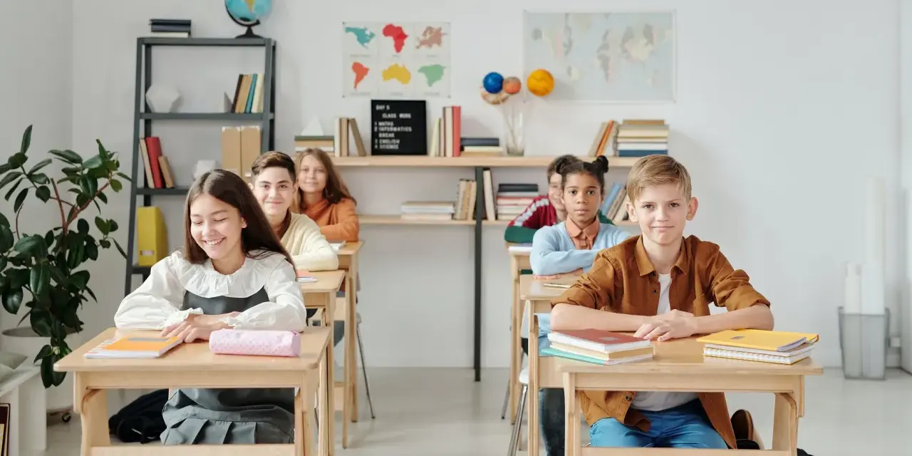 Uczniowie siedzą w ławkach w klasie, która wygląda jak szkoła średnia w Niemczech.