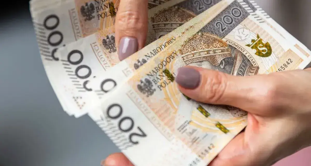 Dłoń trzyma stos banknotów 200 zł. To może być pożyczka od rodziny na nieprzewidziane wydatki.