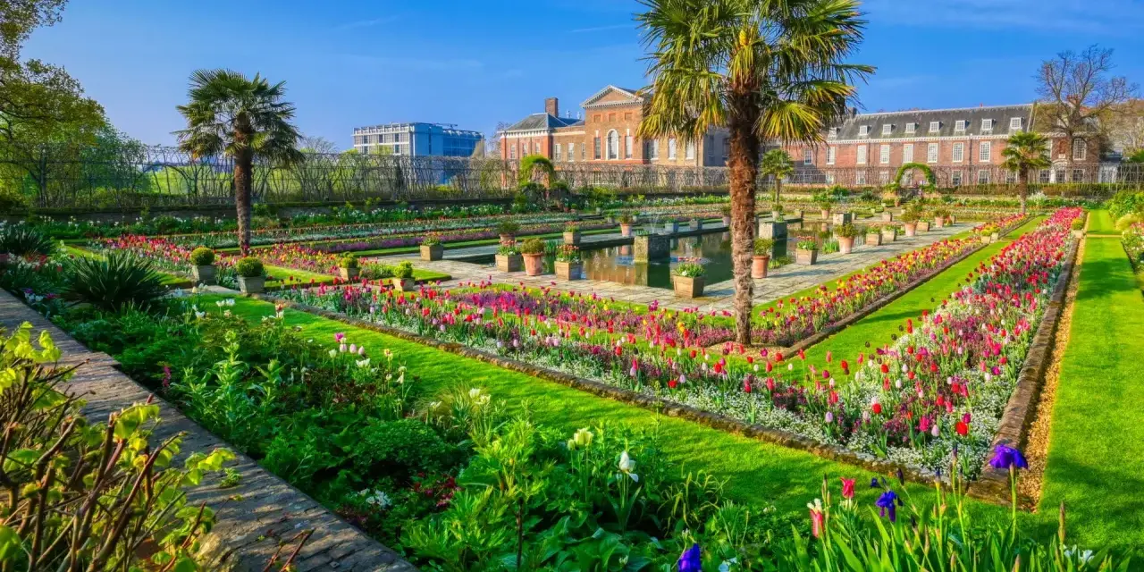 Kwiatowe rabaty i palmy w ogrodach Kensington Palace, Londyn.