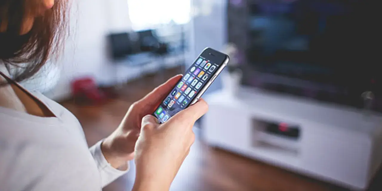 Kobieta trzyma w dłoniach iPhone A1586, przeglądając aplikacje.