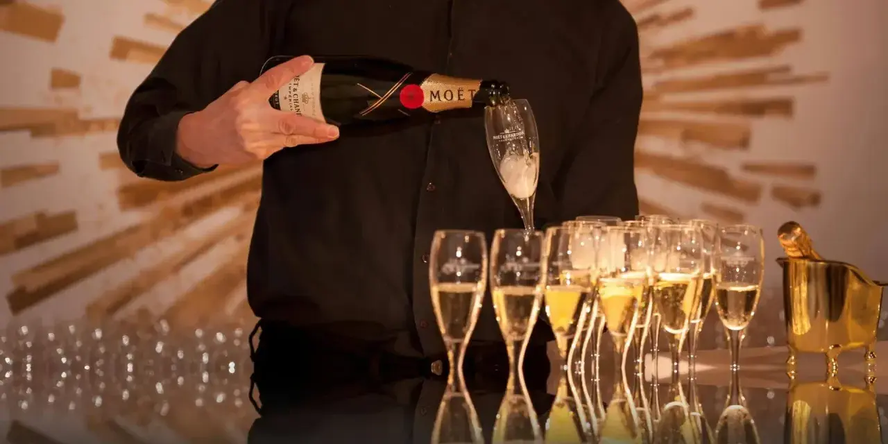 Kelner nalewa szampan Moët & Chandon do kieliszków, przygotowując się do wesela.
