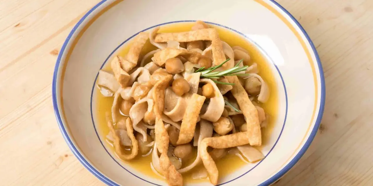 Piatto di ciceri e tria, pasta fresca con ceci e croccanti straccetti fritti, guarnito con rosmarino.