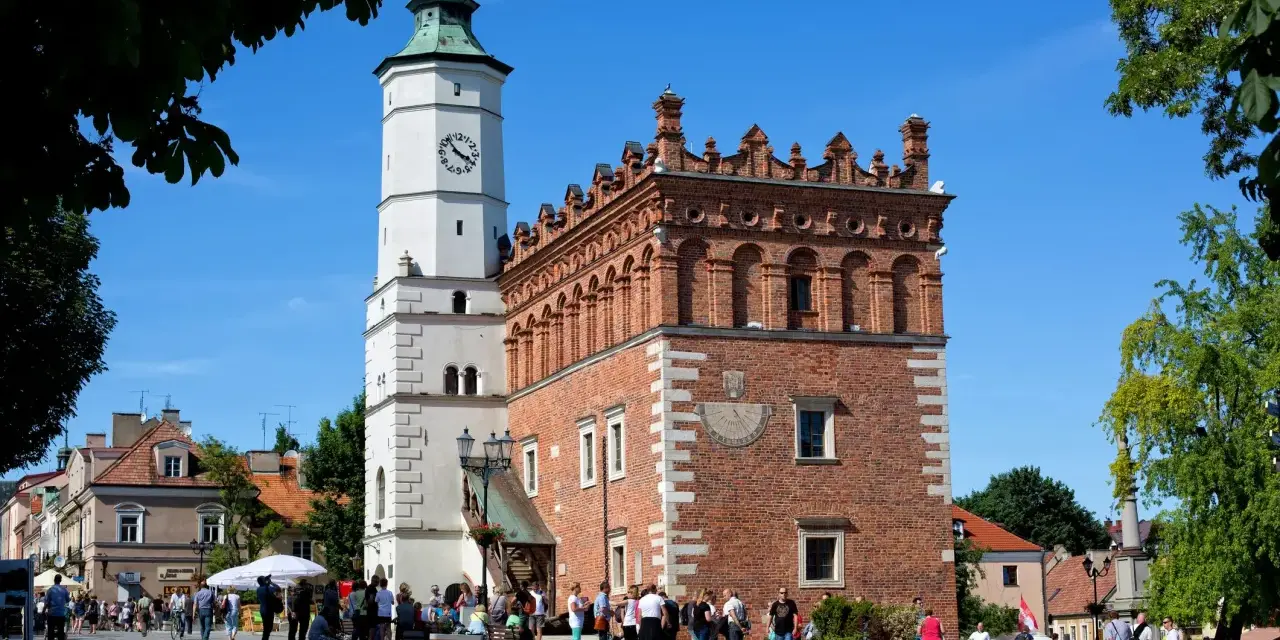 Ratusz w Sandomierzu z zegarem i zegarem słonecznym. Spacerujący ludzie na rynku, ciekawe miejsca Sandomierza.