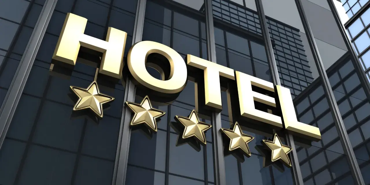 Złote litery "HOTEL" i pięć gwiazdek na nowoczesnym budynku. Spełnia hotel 4 gwiazdki wymagania luksusu i komfortu.