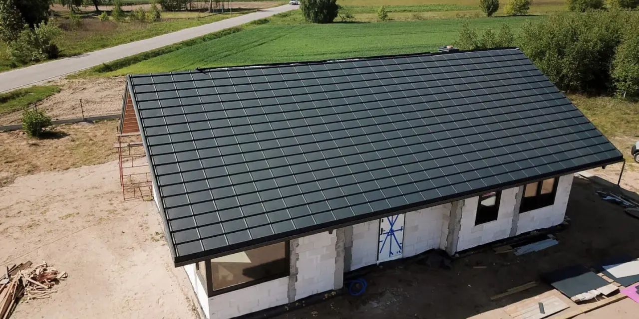 Nowy dom w budowie z ciemnoszarym dachem, widok z góry.