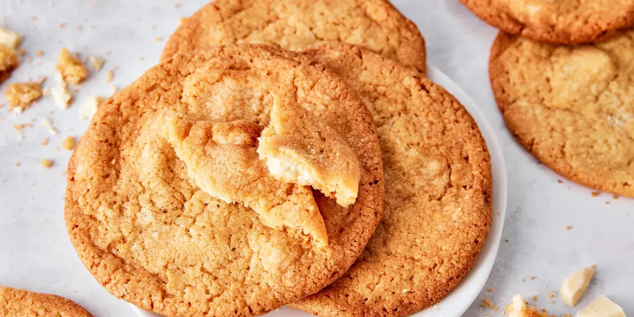 Saftige white chocolate cookies, eine davon angebrochen, mit Stückchen weißer Schokolade und Krümeln daneben.