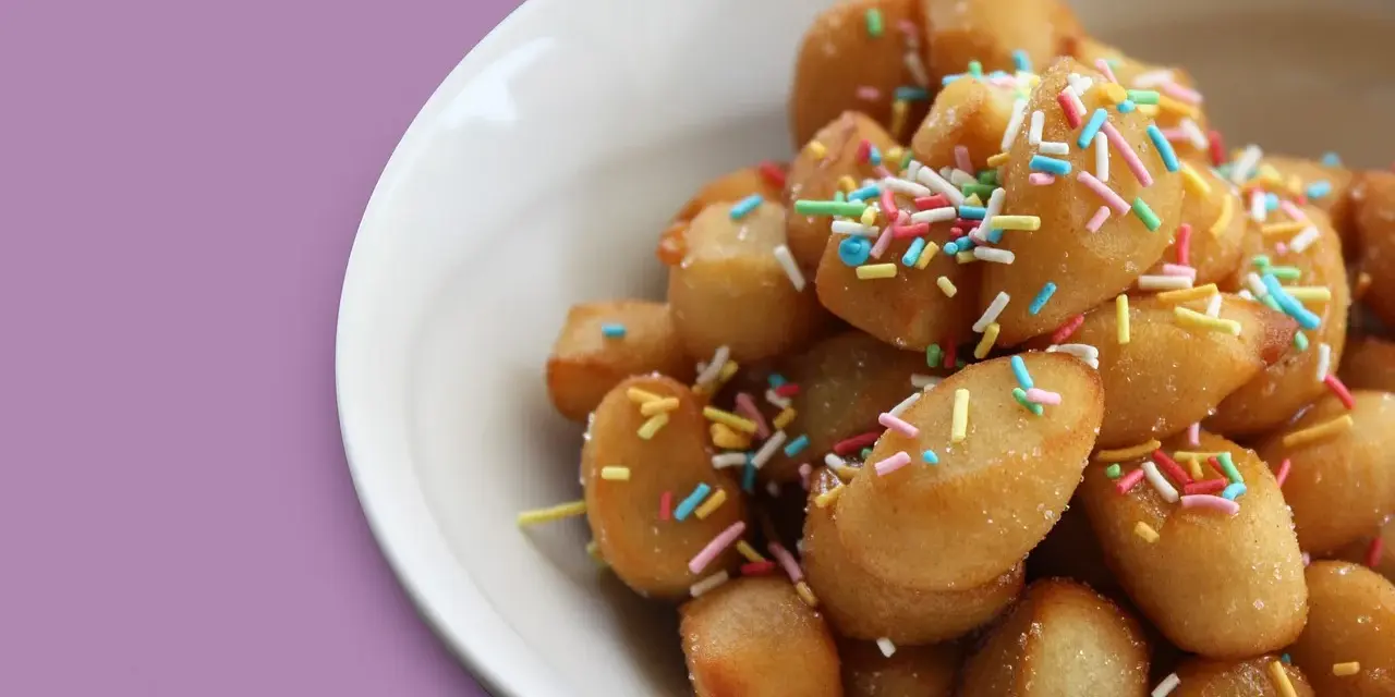 Un piatto di dolci tipici pugliesi, piccole palline dorate cosparse di zuccherini colorati, invitano a un assaggio di tradizione.