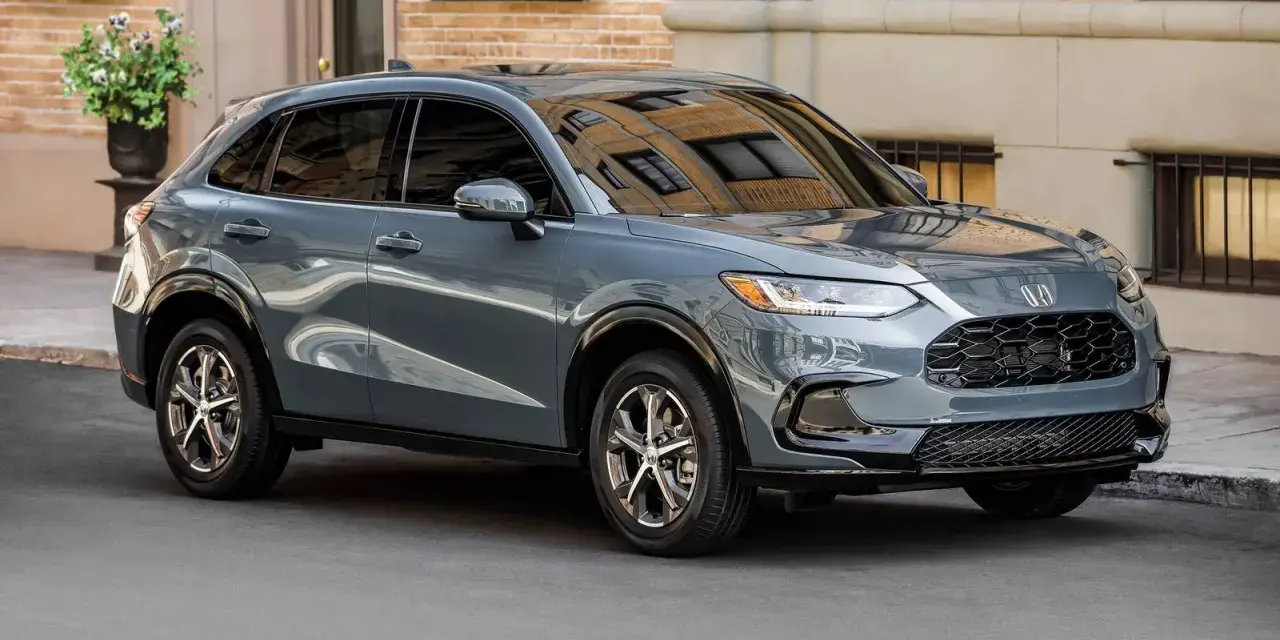Elegancki, szary SUV Honda HR-V stoi na ulicy przed budynkiem z cegły.