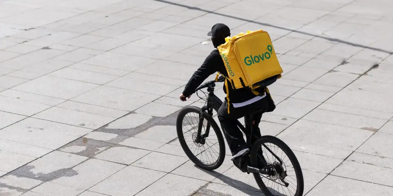 Kurier Glovo na rowerze z charakterystyczną żółtą torbą. Praca w dostawie to jego codzienne wyzwanie.