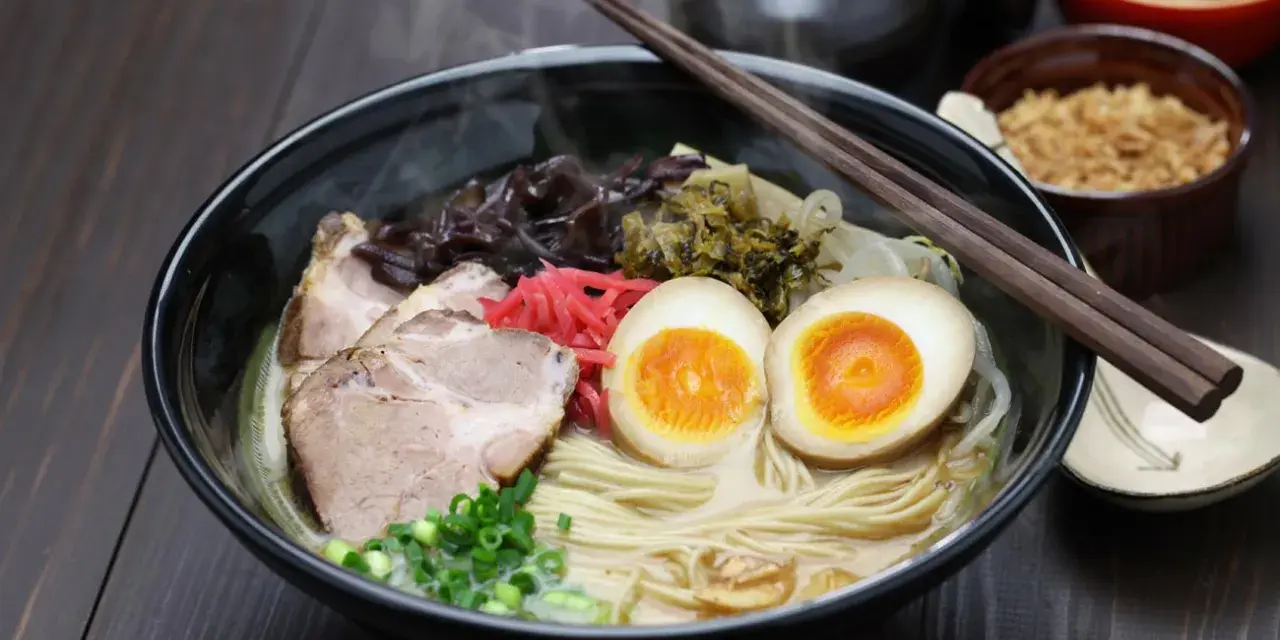 Pyszny ramen co to? Aromatyczny bulion, makaron, plastry wieprzowiny, jajko na pół, szczypiorek i marynowane dodatki.