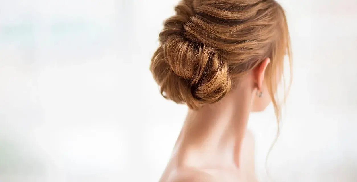 Eleganckie fryzury na wesele dla mamy: misternie upięty kok z rudych włosów, idealny na uroczystość.