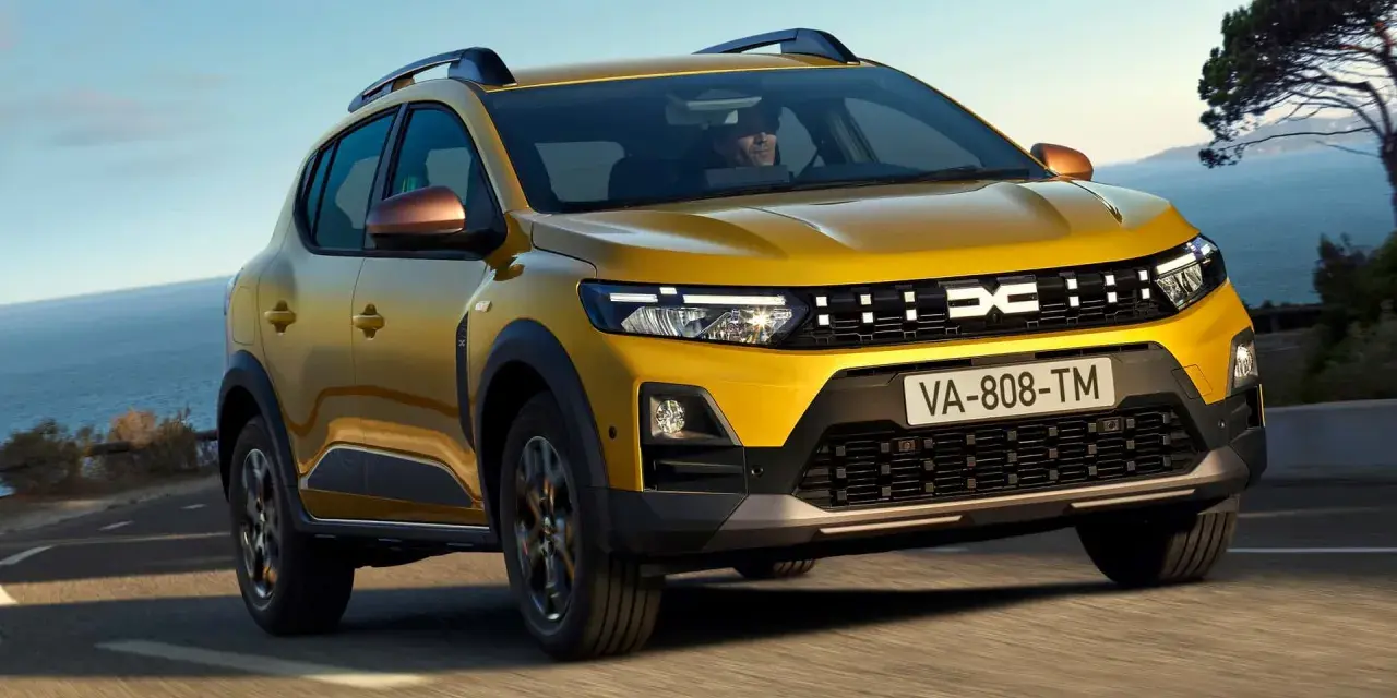 Żółty Dacia Duster, jeden z wielu popularnych dacia modele, jedzie po krętej drodze nad morzem.