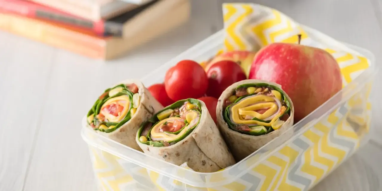 Kolorowy lunchbox z tortillami, jabłkami i pomidorkami. Idealne zdrowe przekąski dla dzieci na szkolny dzień.