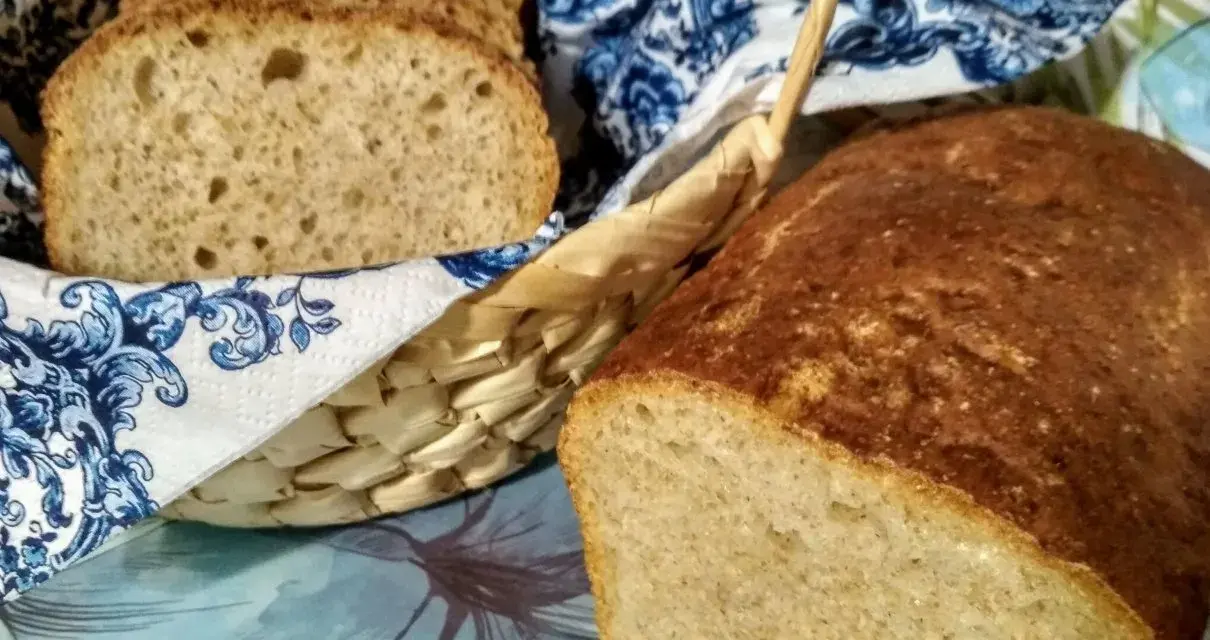 Chleb na piwie, świeżo upieczony, z chrupiącą skórką i puszystym wnętrzem. Kromki w koszyku, ozdobionym niebieskim wzorem.