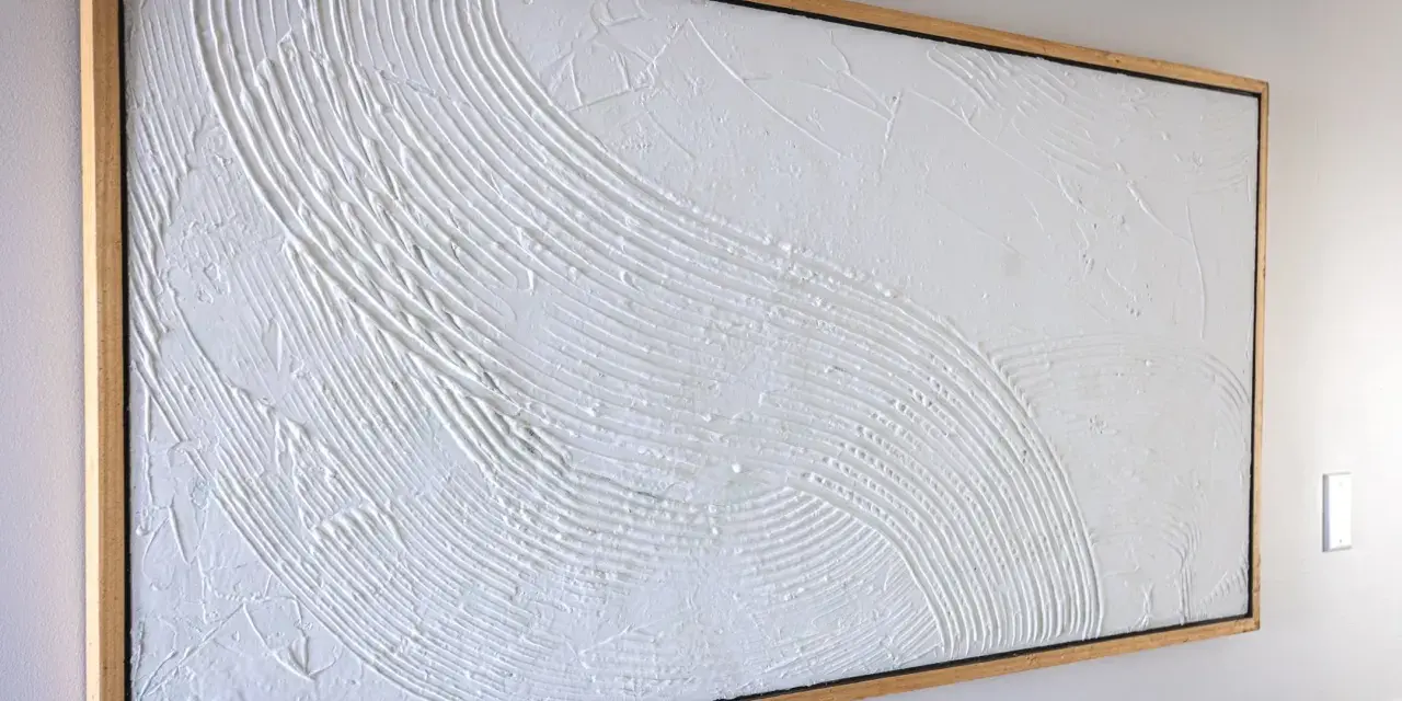 Peinture relief sur toile, texture blanche texturée évoquant des vagues douces dans un cadre en bois.