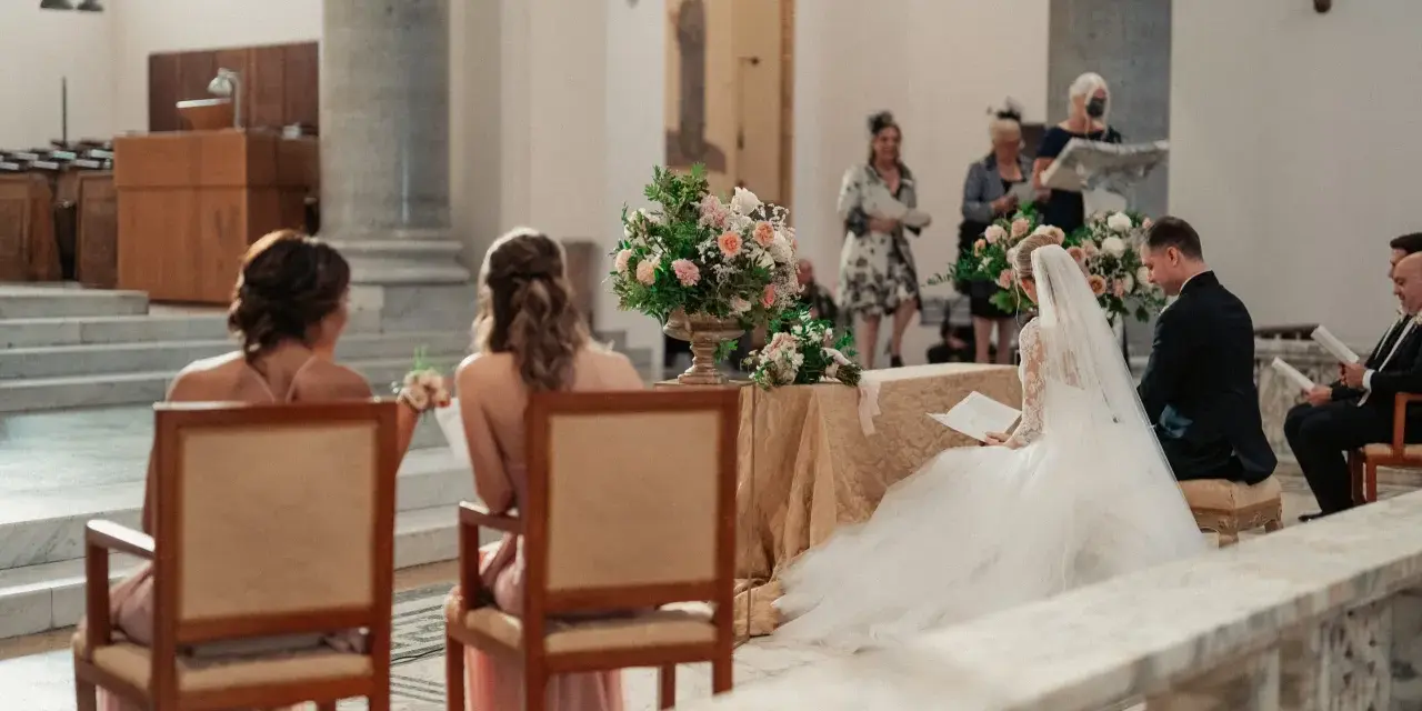 Sposi in chiesa, con la sposa in abito bianco e il velo. Si possono avere 6 testimoni di nozze, ma qui ne vediamo solo alcuni.