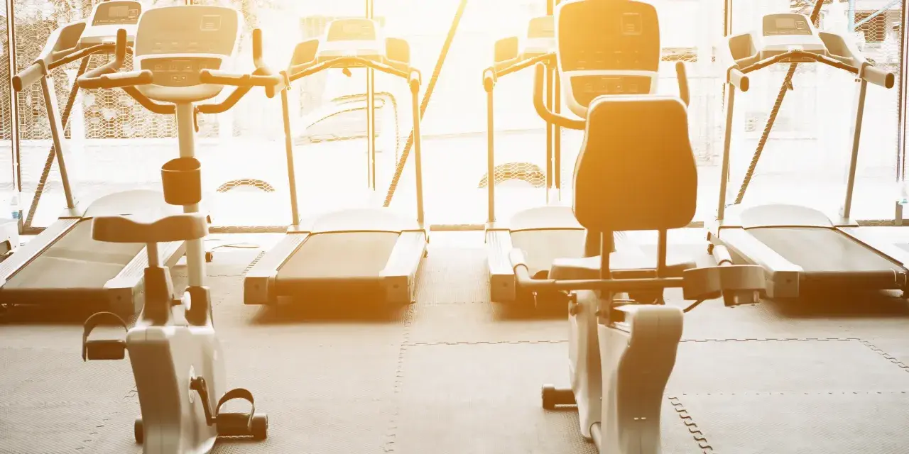 Rzędy bieżni i rowerów stacjonarnych czekają na trening. Idealne miejsce na cardio na siłowni, by poczuć energię.