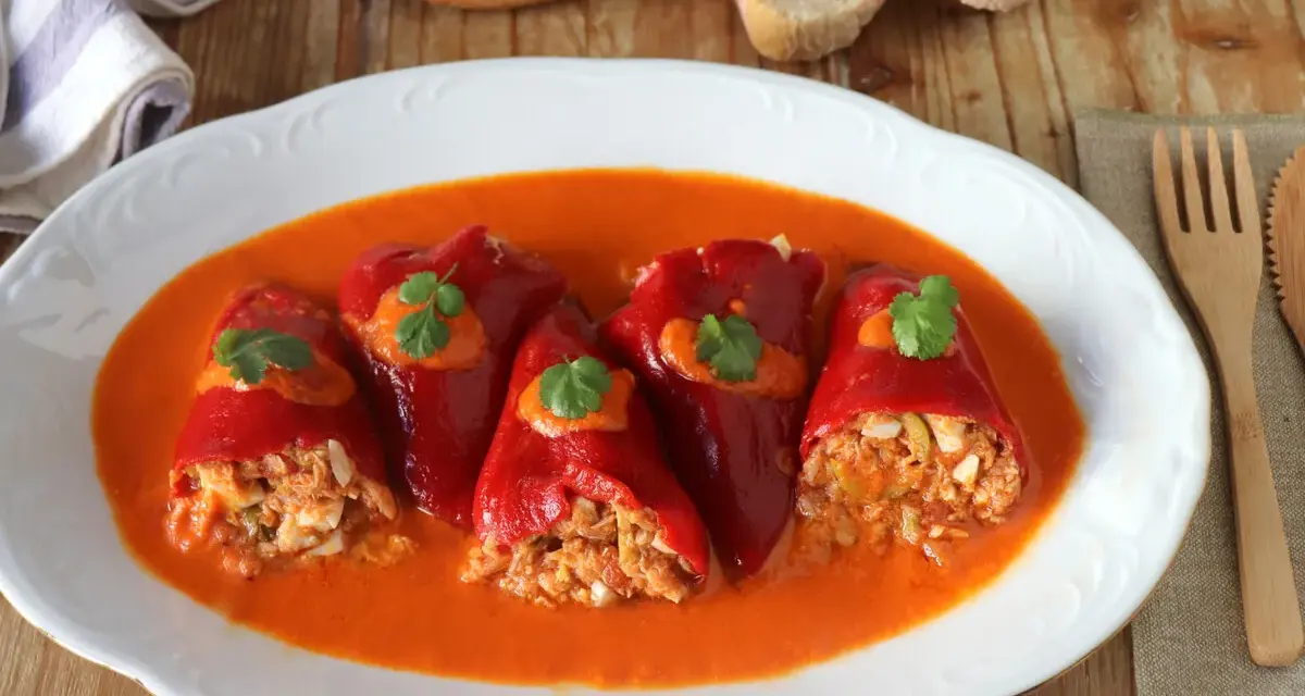 Pimientos del piquillo rellenos de atún y huevo, servidos en una salsa roja cremosa.