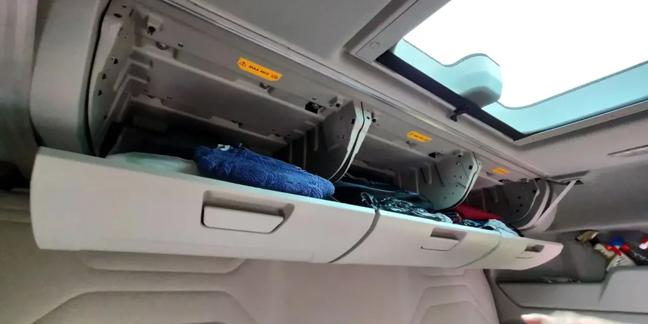 Schowek w kabinie Ford F-Max z niebieskim ręcznikiem i innymi przedmiotami.
