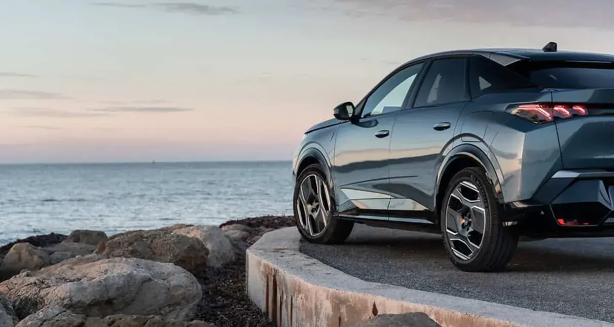 Nowy Peugeot 3008 hybryda na tle spokojnego morza i skalistego wybrzeża.