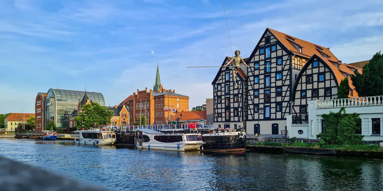 Bydgoszcz atrakcje: Łucznik na linie nad Brdą, nowoczesna architektura i zabytkowe kamienice tworzą malowniczy widok.
