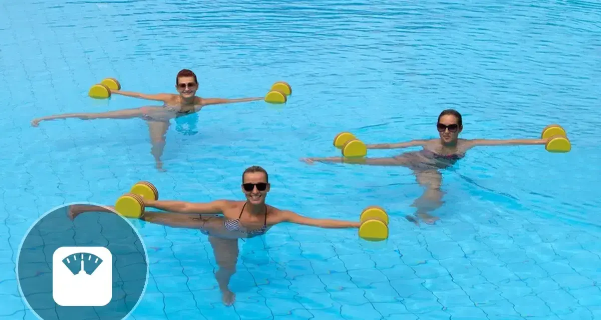 Trois femmes souriantes font un exercice aquagym dans une piscine, tenant des haltères flottants jaunes pour un entraînement tonique.