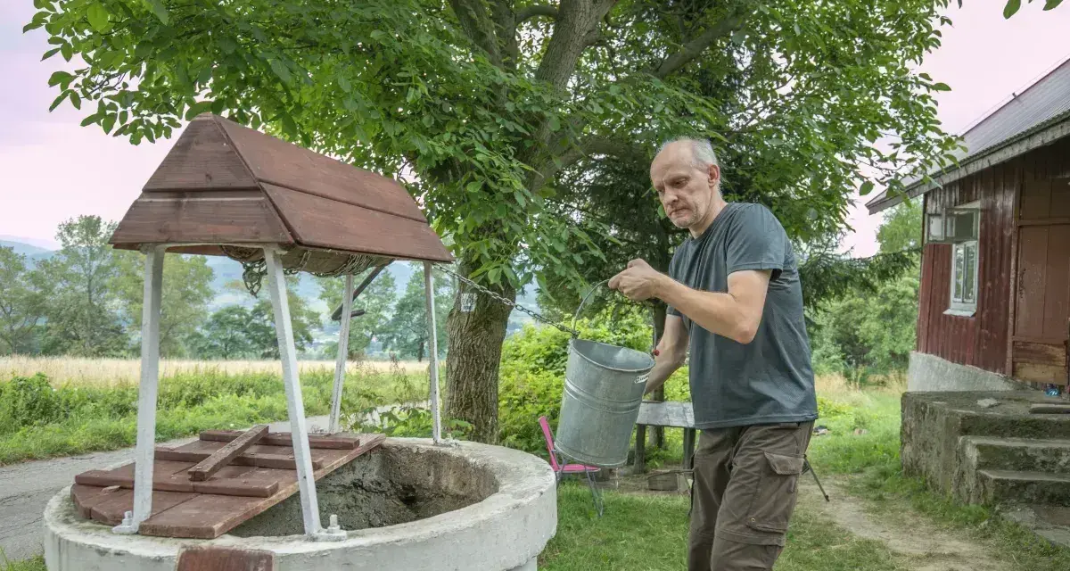 Mężczyzna czerpie wodę z **studni głębinowej**. Czy posiada **pozwolenie** na jej budowę?